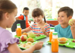 Kinder sitzen in der Kantine und genießen die Mittagspause.