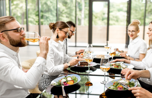 Auf dem Bild sind Geschäftsleute zu sehen, die gemeinsam einen köstlichen und gesunden Mittagstisch genießen. Sie sitzen an einem eleganten Tisch in einem Restaurant.