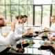 Auf dem Bild sind Geschäftsleute zu sehen, die gemeinsam einen köstlichen und gesunden Mittagstisch genießen. Sie sitzen an einem eleganten Tisch in einem Restaurant.