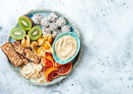Gesunder Snackteller mit Energy Balls, Kiwi und Hummus für Schulen