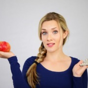 Plfanzliche Ernährung. Junge Frau hat einen Apfel auf ihrer Handfläche und hält in der anderen Hand Tabletten.
