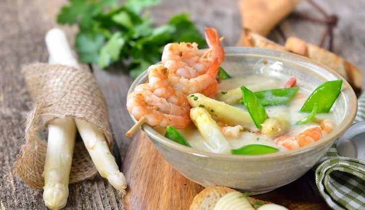 Spargelcremesuppe, garniert mit Garnelen und grünen Bohnen.