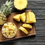 Frisch geschnittene Ananasstücke und eine ganze Ananas auf einem Holzbrett – ein tropischer Genuss voller Vitamine und Frische, perfekt für gesunde Ernährung.