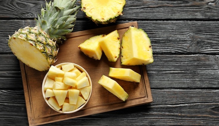 Frisch geschnittene Ananasstücke und eine ganze Ananas auf einem Holzbrett – ein tropischer Genuss voller Vitamine und Frische, perfekt für gesunde Ernährung.