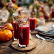 Catering-Tisch mit Mehrweg-Gläsern gefüllt mit Rote-Bete-Saft, saisonales Herbstgemüse (Kürbis, Rote Bete, Äpfel) als Dekoration, moderne Bio-Catering-Atmosphäre, natürliche Holztische, frische Farben, freundliche Stimmung, perfekt für Event oder Kindergarten-Catering