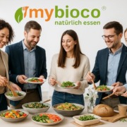 mybioco-_Nachhaltiges_Catering Nachhaltiges Catering von mybioco in einem modernen, hellen Büro – liebevoll angerichtetes Buffet mit regionalen und saisonalen Bio-Speisen, frischen Salaten und knusprigem Brot. Junge Menschen im modernen Casual-Office-Look genießen gemeinsam das Essen in entspannter, freundlicher Atmosphäre. Das mybioco-Logo steht für Genuss mit Verantwortung und echte Nachhaltigkeit.