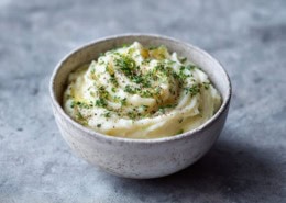 Selleriepüree in einer minimalistischen Keramikschale, cremige Textur, mit Kräutern bestreut, weiches natürliches Licht, skandinavisches Food-Styling.
