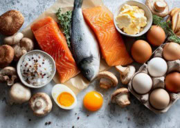 Flatlay von vitamin-D-reichen Lebensmitteln: Lachs, Hering, Eier, Pilze, Leber, angereicherte Lebensmittel – bunt, sauber, mit hellem natürlichem Licht