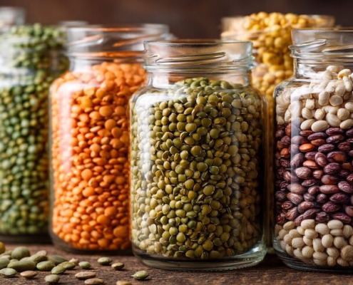 Nahaufnahme von Hülsenfrüchten, Linsen, Kichererbsen, Erbsen in Glasgefäßen, pflanzliche Eiweißquellen, vegan, nachhaltig, ruhiger Hintergrund, natürliche Texturen, warmes Licht, Editorial Food Photography, ultra realistic, high detail