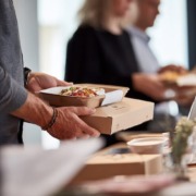 Verpflegung im Unternehmen ohne Kantine, moderne Büroumgebung, Mitarbeitende sitzen gemeinsam an einem Tisch, Lunch-Bowls und warme Mahlzeiten, natürlich angerichtet, ruhige, professionelle Stimmung, Tageslicht, keine Kantine sichtbar, authentischer Arbeitsalltag