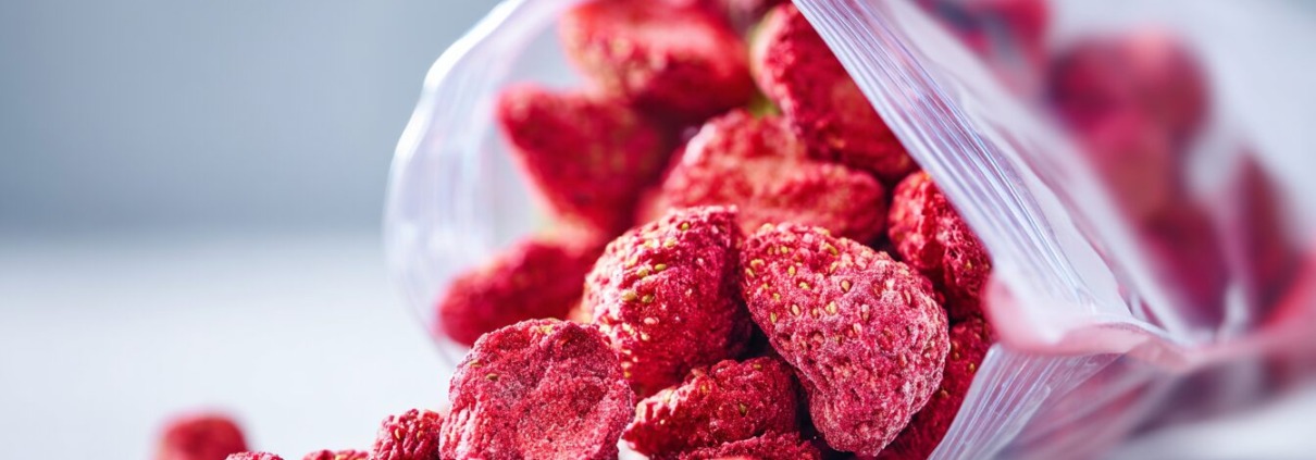 Offene, nachhaltige Verpackung mit zerkleinerten getrockneten Erdbeeren, fast wie Pulver, , natürliche unperfekte Stücke sichtbar, klare und gut lesbare Inhaltsstoffliste auf der Verpackung, cleanes modernes Design, sanfte natürliche Lichtstimmung, ehrliche Produktdarstellung ohne Inszenierung
