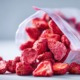 Offene, nachhaltige Verpackung mit zerkleinerten getrockneten Erdbeeren, fast wie Pulver, , natürliche unperfekte Stücke sichtbar, klare und gut lesbare Inhaltsstoffliste auf der Verpackung, cleanes modernes Design, sanfte natürliche Lichtstimmung, ehrliche Produktdarstellung ohne Inszenierung