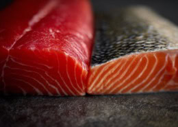 Split-screen Darstellung verschiedener Lachsfilets im Querschnitt, deutlicher Unterschied in Farbe und Fettmarmorierung zwischen Atlantischem Lachs, Sockeye, Coho und Königslachs