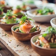 Brainfood Business Lunch Catering mit kleinen Schalen, Lachs, Avocado, Nüssen und frischem Gemüse, modern angerichtet auf Holztisch im Bio-Stil