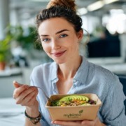 Frau im Büro mit nachhaltiger Bowl in umweltfreundlicher Verpackung von mybioco Bio Catering