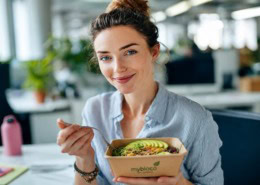 Frau im Büro mit nachhaltiger Bowl in umweltfreundlicher Verpackung von mybioco Bio Catering