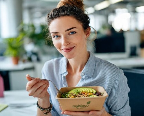 Frau im Büro mit nachhaltiger Bowl in umweltfreundlicher Verpackung von mybioco Bio Catering